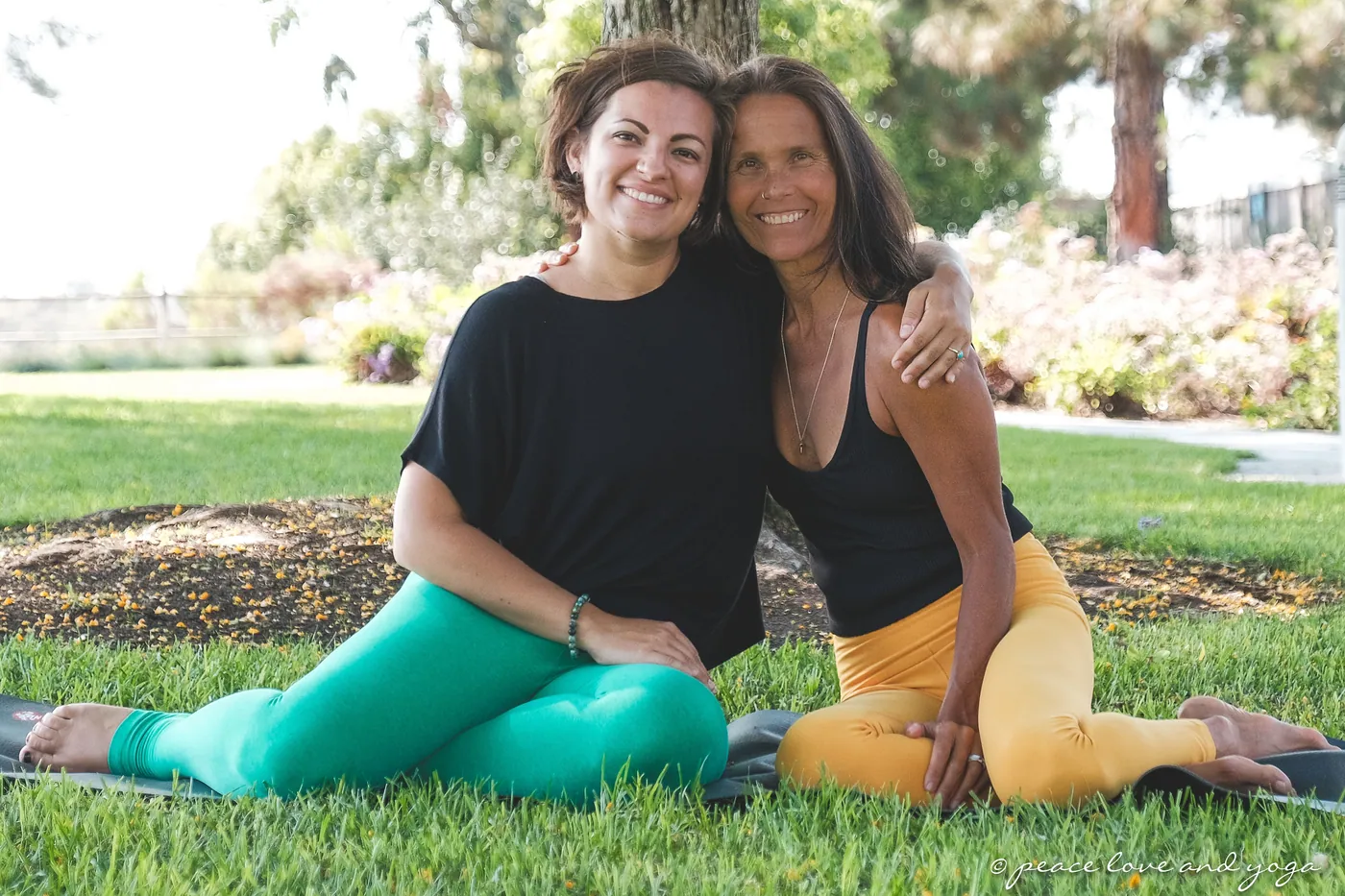 Jess and Monique, the owners, seated together on their mats under the trees in a Carlsbad park